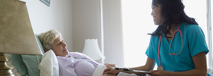 Healthcare professional smiling with bedridden patient