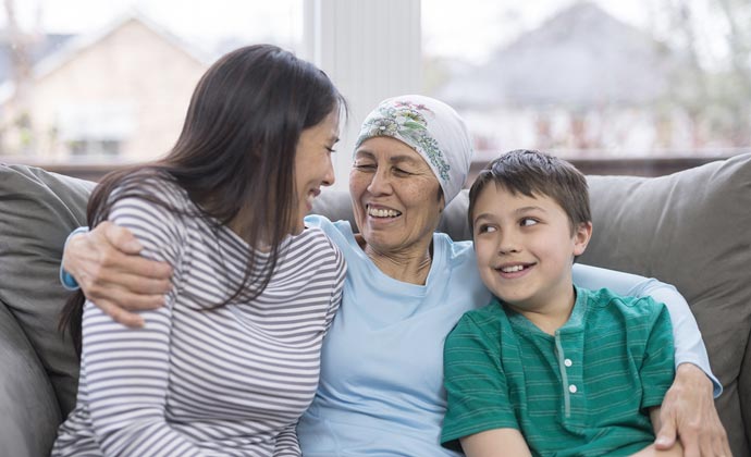 Una mujer con cáncer abraza a su hija y a su nieto en un sofá en su casa