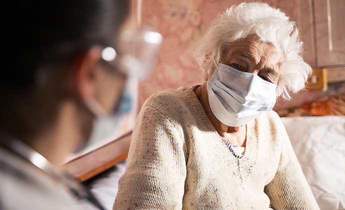 A doctor visits with an elderly female patient at home