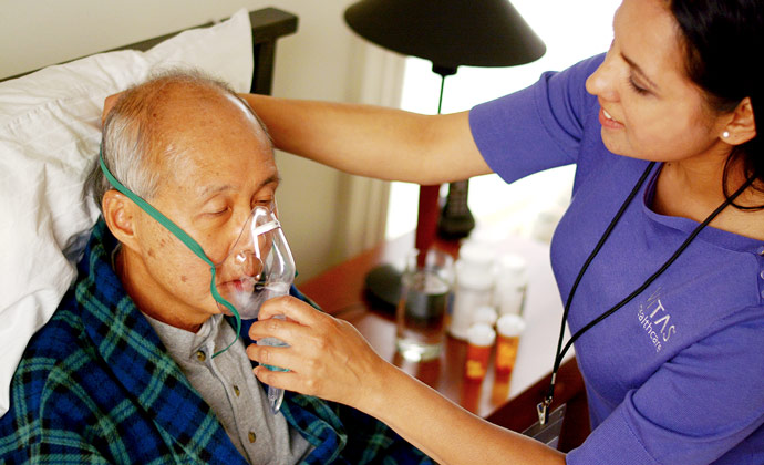 A VITAS nurse helps a patient secure his oxygen mask