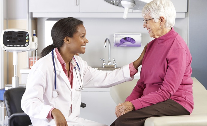 A physician talks with a patient in an exam room