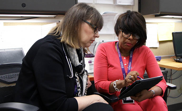 A VITAS team member shows information on a tablet to another healthcare professional