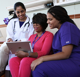 Una integrante del equipo de VITAS habla con otras dos profesionales de asistencia médica