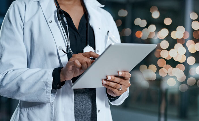 Un médico y la esposa de un paciente miran la pantalla de la computadora juntos