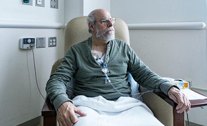 A man with an IV line sits in a chair