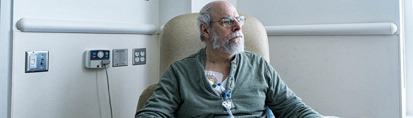 A man with an IV line sits in a chair