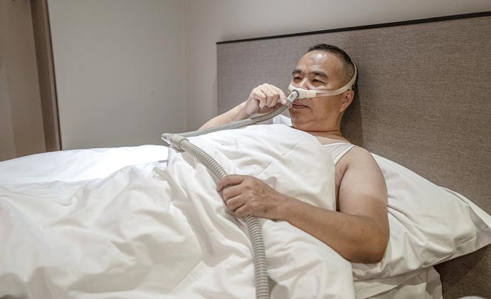 A man lying in bed at home receiving oxygen therapy