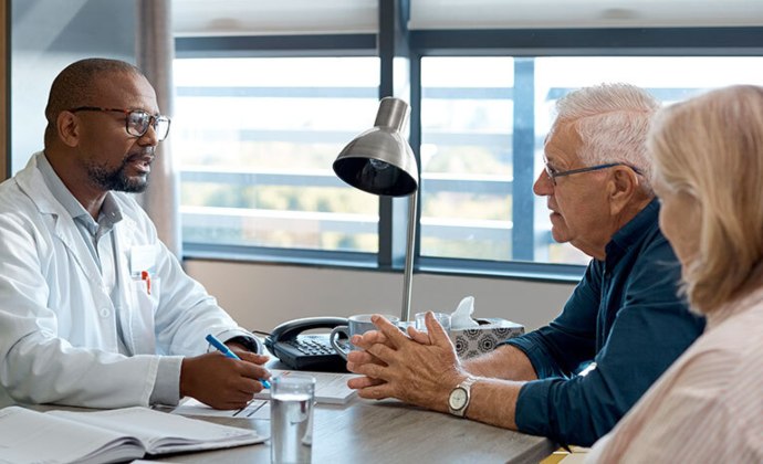 A physician talks with a couple at a desk in his office