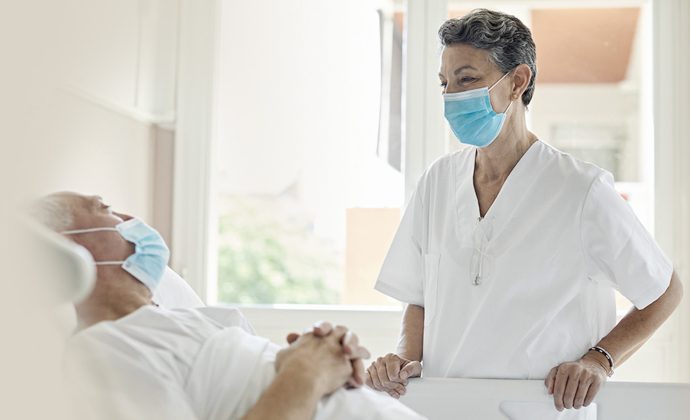 Un clínico habla con un paciente que está recostado en la cama