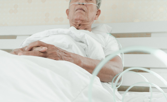 Nakahiga sa isang hospital bed ang isang lalaki na may nasal cannula para sa karagdagang oxygen