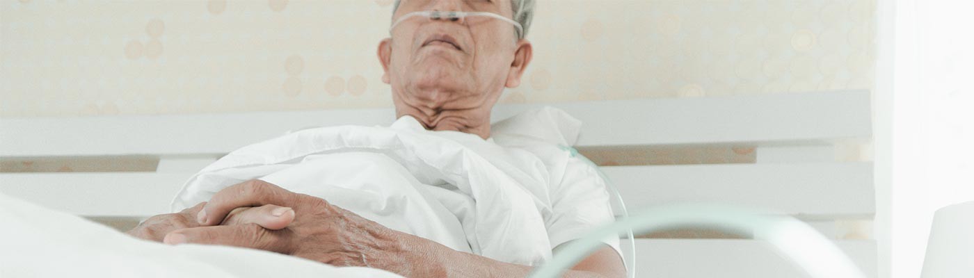 Nakahiga sa isang hospital bed ang isang lalaki na may nasal cannula para sa karagdagang oxygen