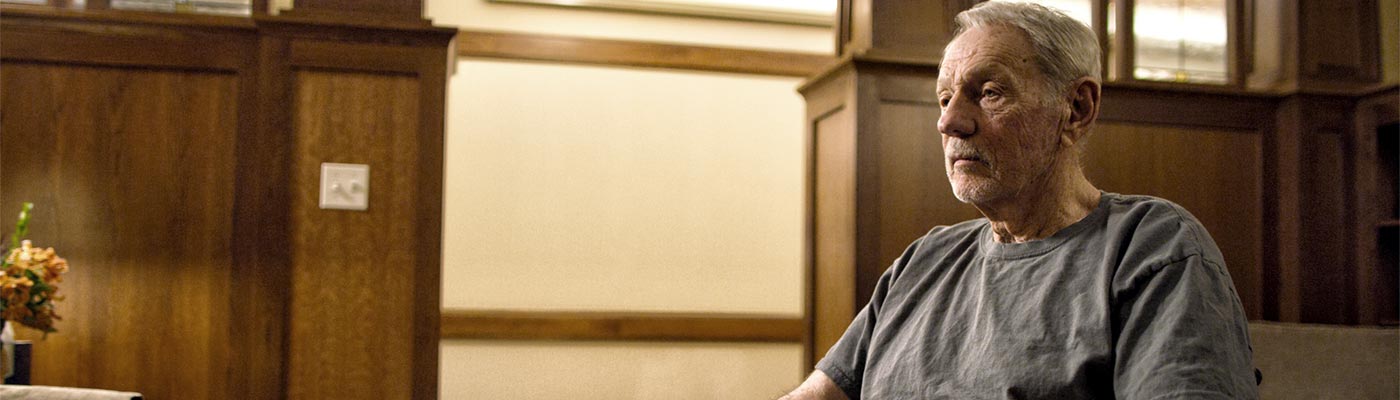 Un hombre se sienta en una silla con una manta sobre su regazo