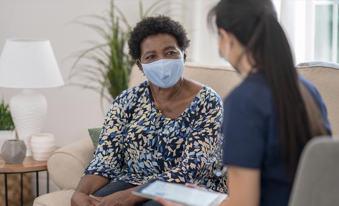 A clinician visits with a patient in her living room