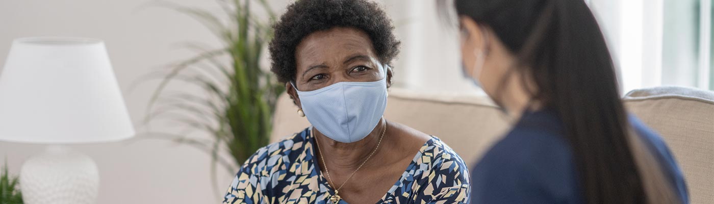 A clinician visits with a patient in her living room