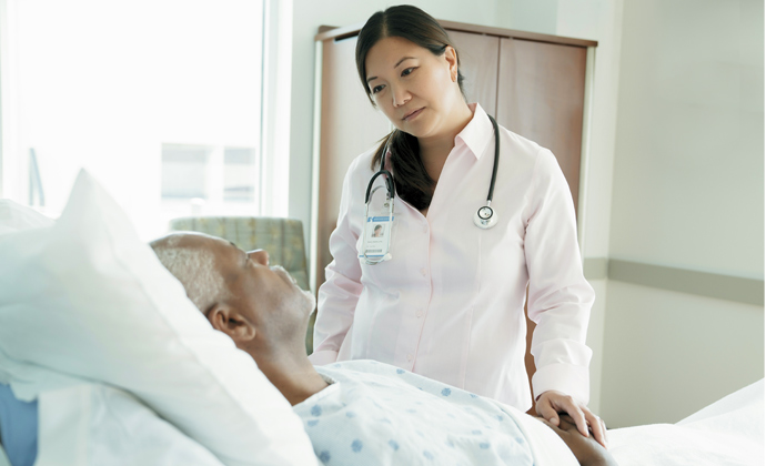 A physician talks with a patient who is lying in bed