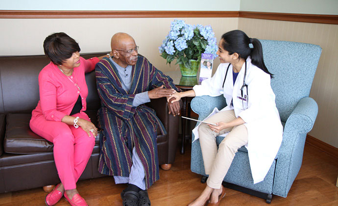 A VITAS physician talks with a couple seated on a sofa