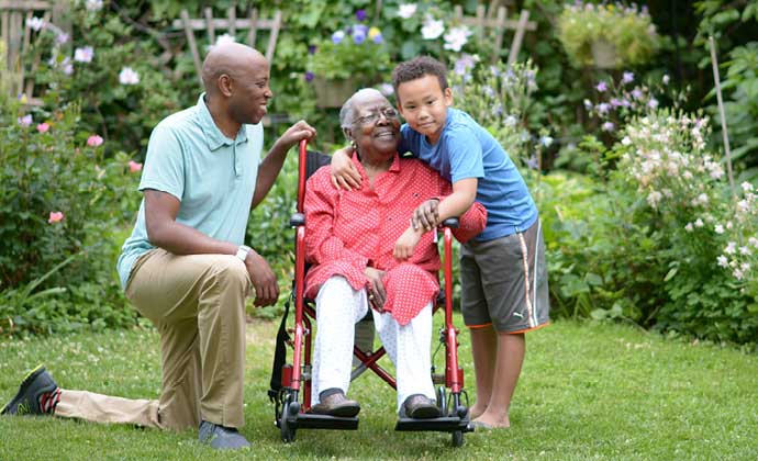 Una mujer en silla de ruedas abraza a su nieto mientras disfruta de un momento en un jardín exterior