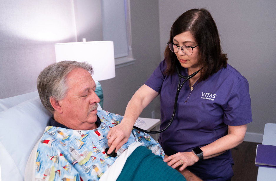 A VITAS nurse uses a stethoscope to check a patient's heart