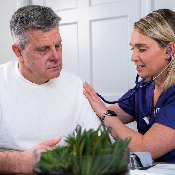 A VITAS physician smiles with a patient who is using a wheelchair