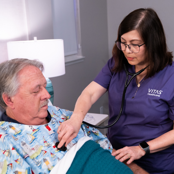 A VITAS physician talks with a woman in an inpatient unit bed