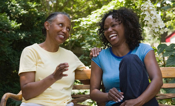 Two people sit on a park bench and smile